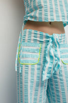 Teal and white striped outfit with a pocket detail on a plain background