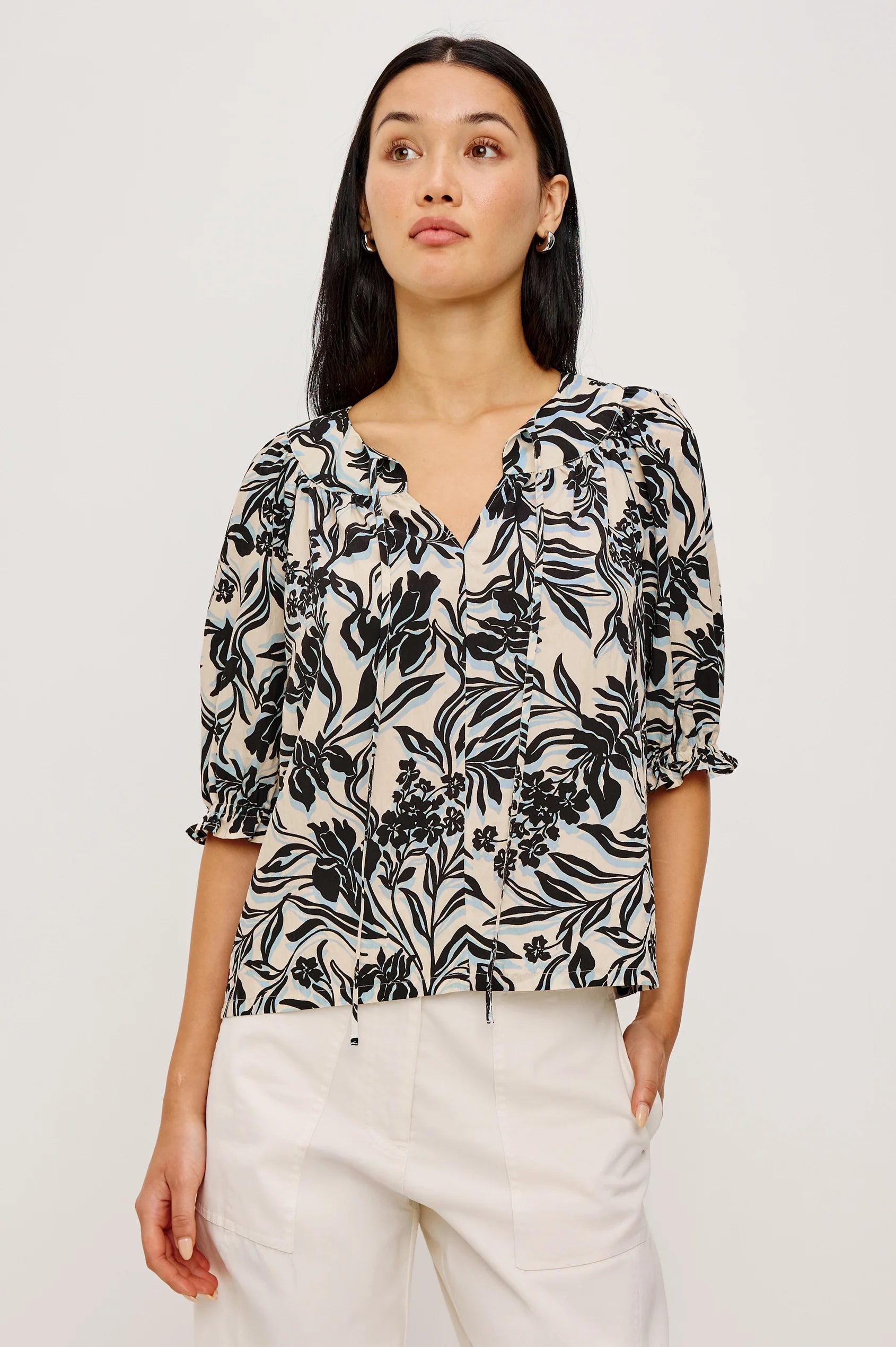 Woman wearing a black floral blouse against a white background