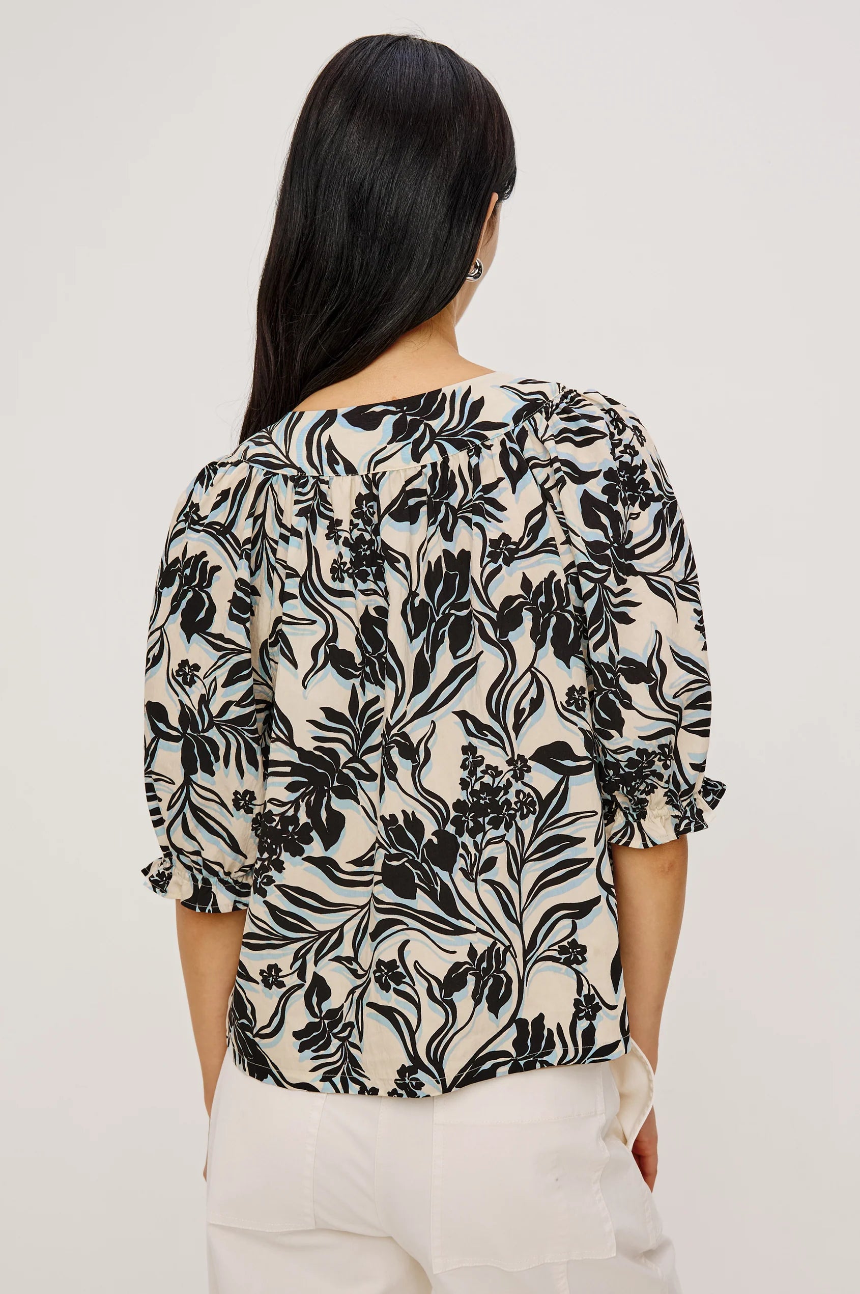 Woman wearing a black floral patterned blouse against a white background