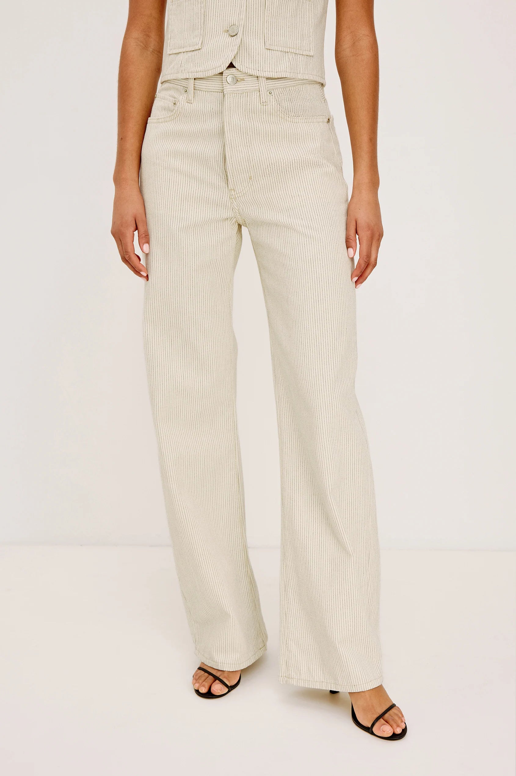 Person wearing beige wide-leg pants on a white background