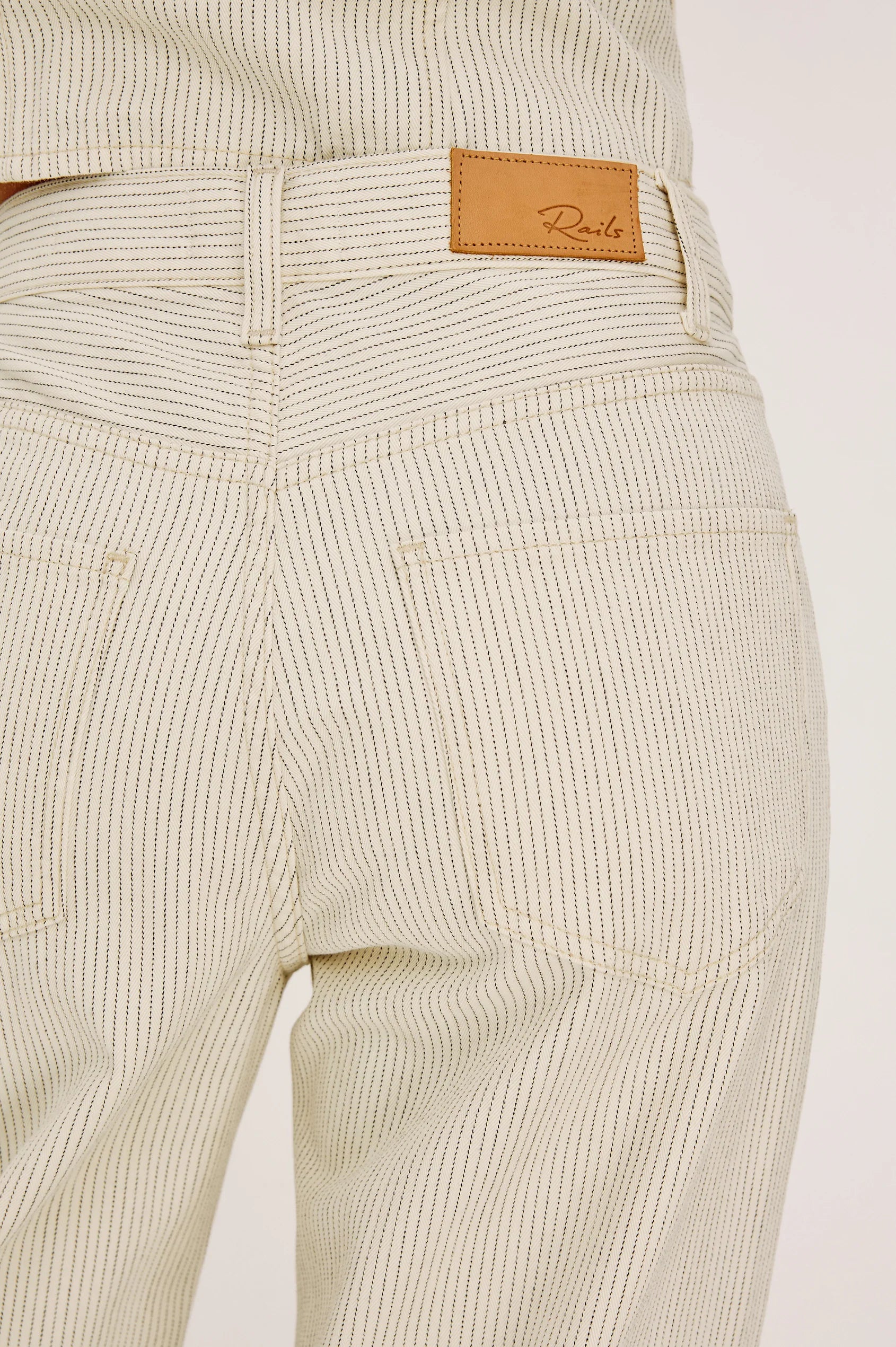 Beige corduroy pants with a brown leather patch on a white background