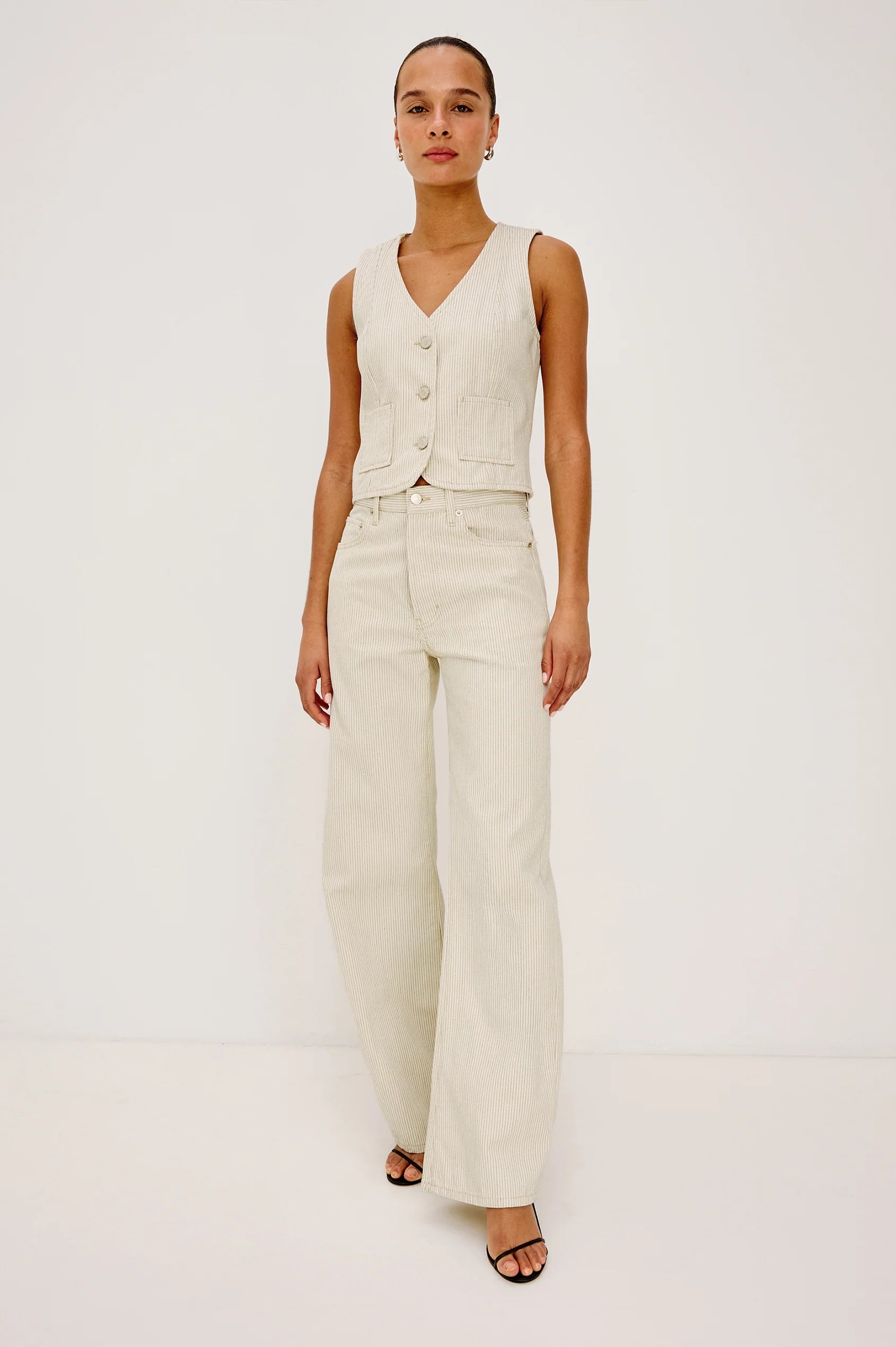 Woman wearing a cream vest and pants on a white background