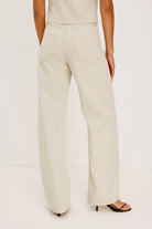 Person wearing a beige suit with wide-leg pants on a white background