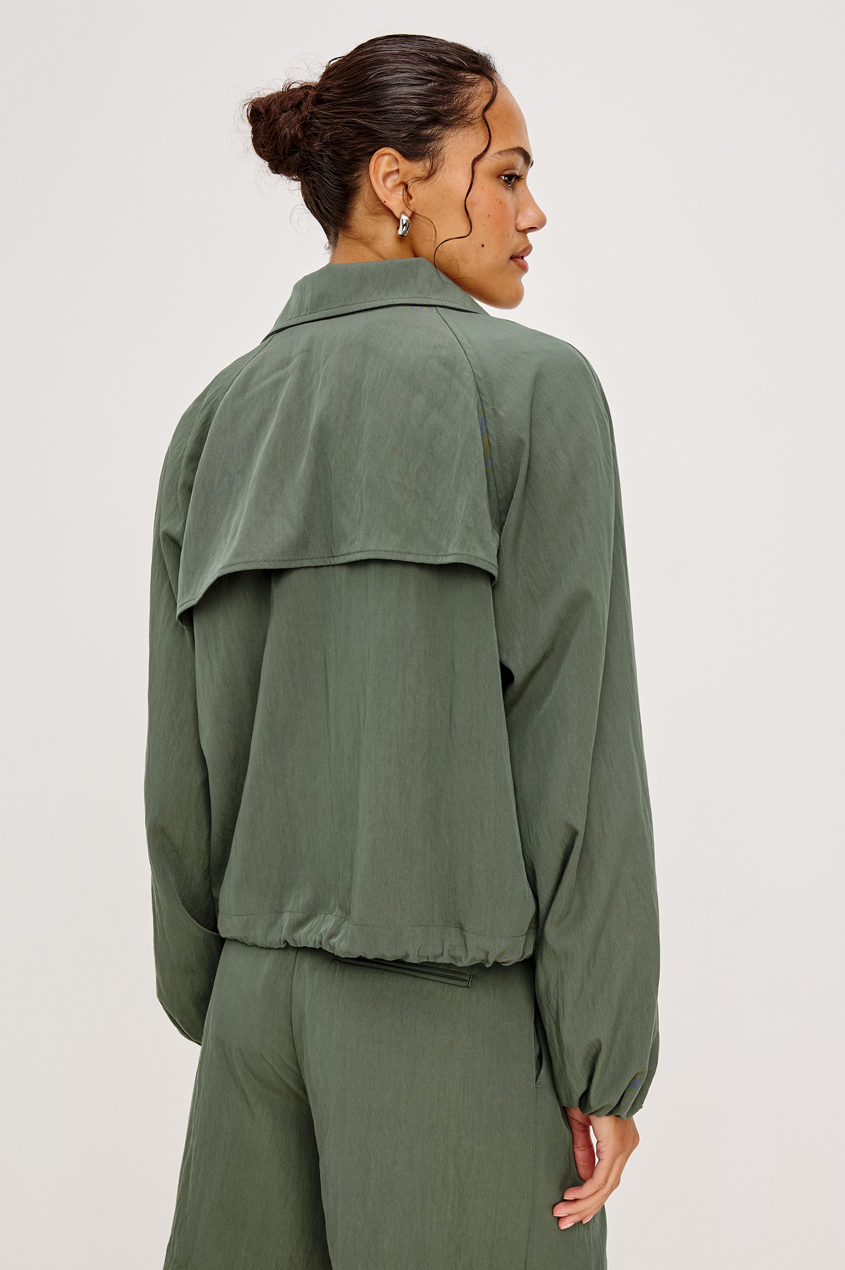 Woman wearing a green jacket and pants on a white background