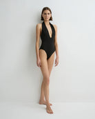 Woman wearing a black swimsuit against a white background