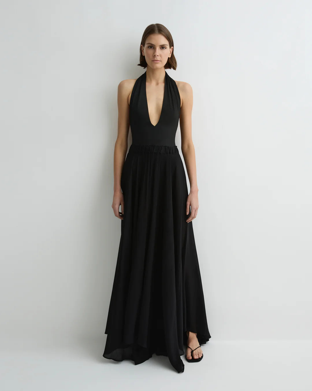Woman wearing a black halter neck gown on a plain background