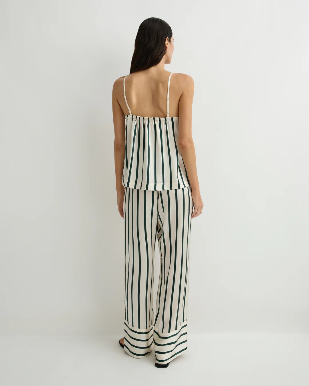 Woman wearing a black and white striped jumpsuit on a plain background