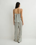 Woman wearing a black and white striped jumpsuit on a plain background