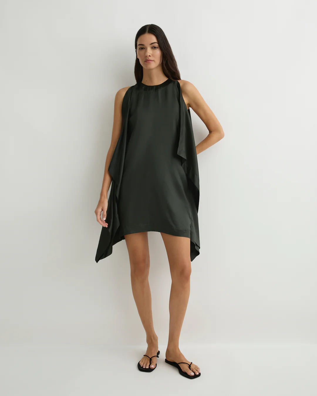 Woman wearing a dark green sleeveless dress on a white background