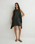 Woman wearing a dark green sleeveless dress on a white background