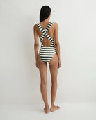 Woman wearing a black and white striped swimsuit on a plain background