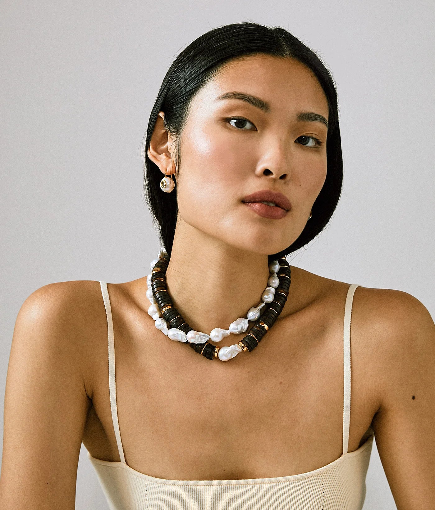 Woman wearing a necklace with a neutral background