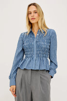 Woman wearing a blue striped shirt and gray pants on a white background
