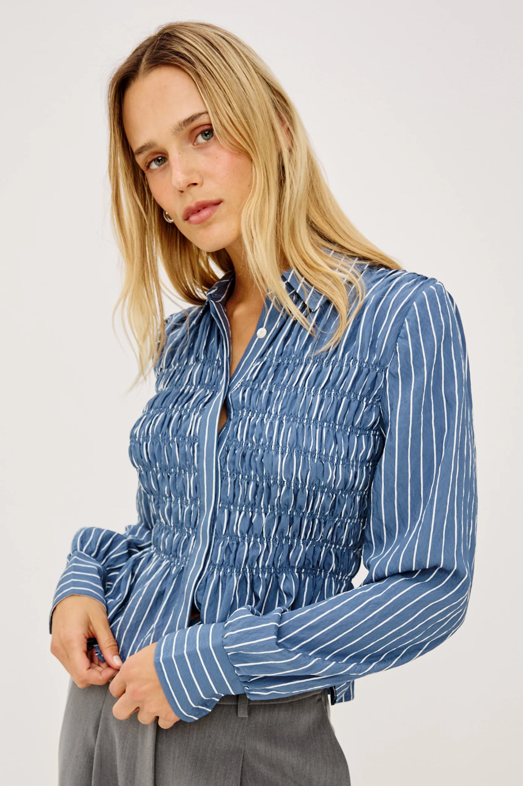 Woman wearing a blue striped shirt against a white background