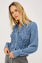 Woman wearing a blue striped shirt against a white background