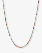 A delicate gold chain necklace adorned with small, colorful gemstones in multiple hues, displayed against a light gray background.