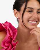 Woman wearing a pink top with ruffled shoulders against a white background