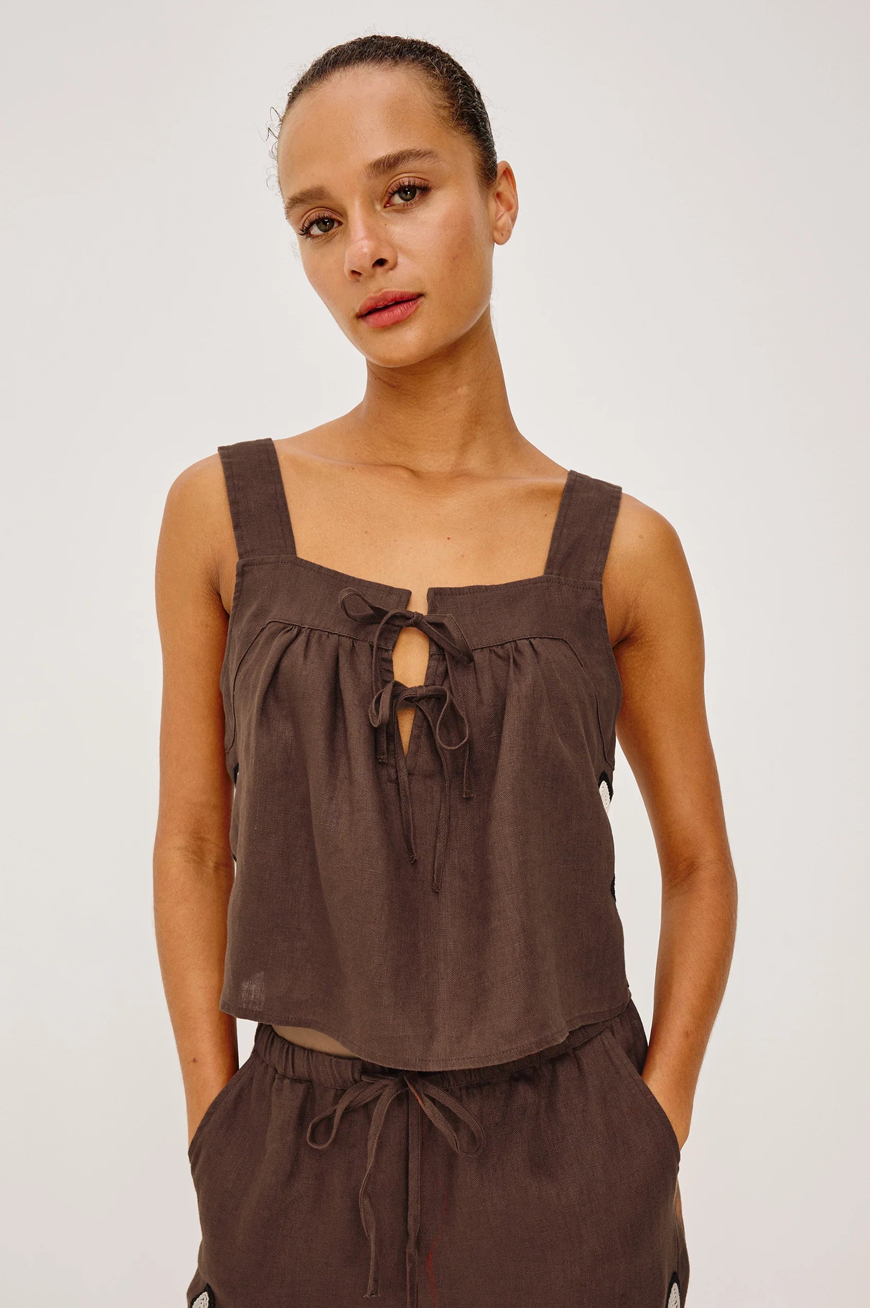 Woman wearing a brown sleeveless top and pants on a white background