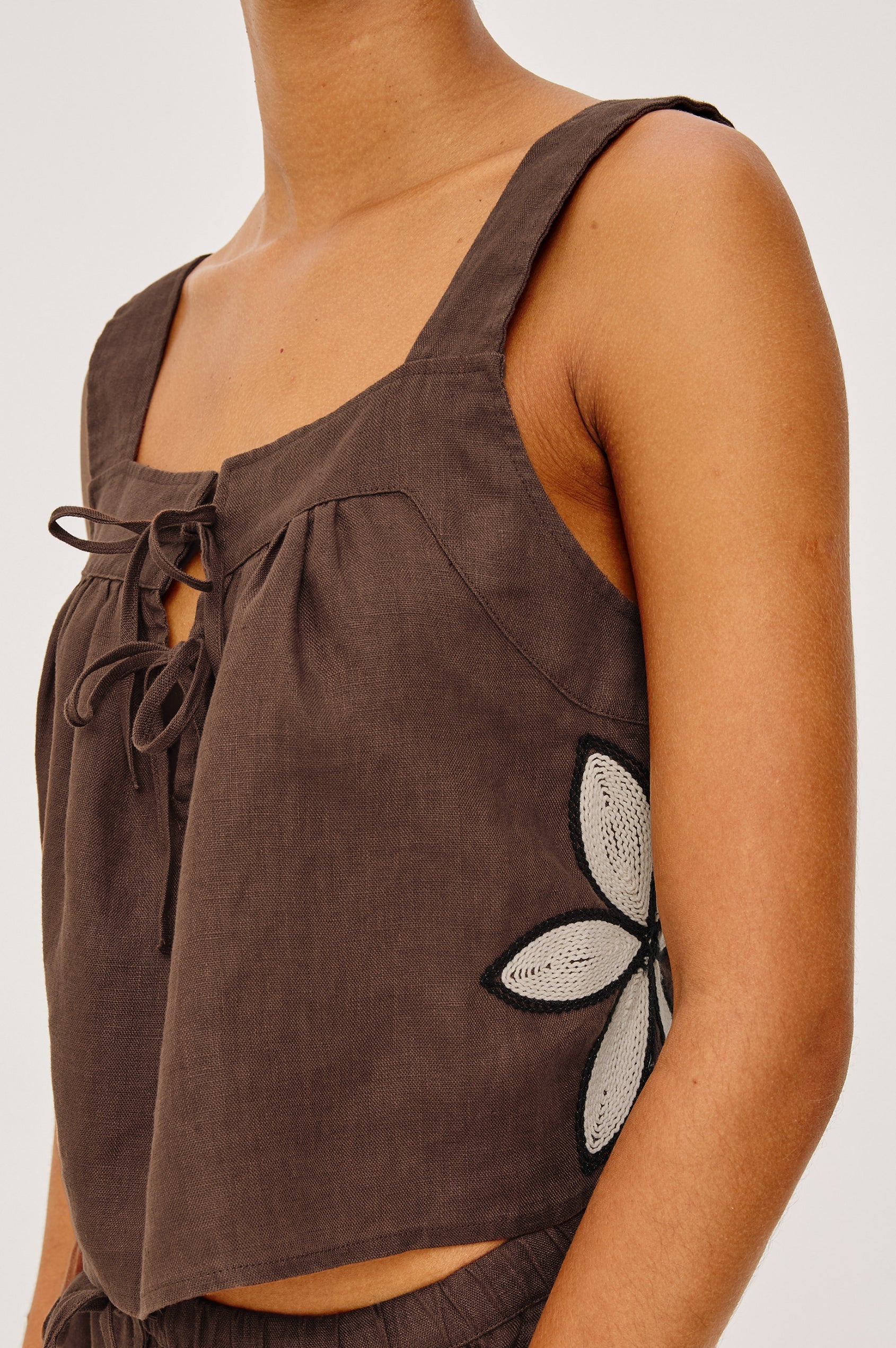Brown sleeveless top with floral embroidery on a neutral background