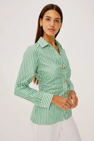 Woman wearing a green and white striped shirt with gold buttons on a white background