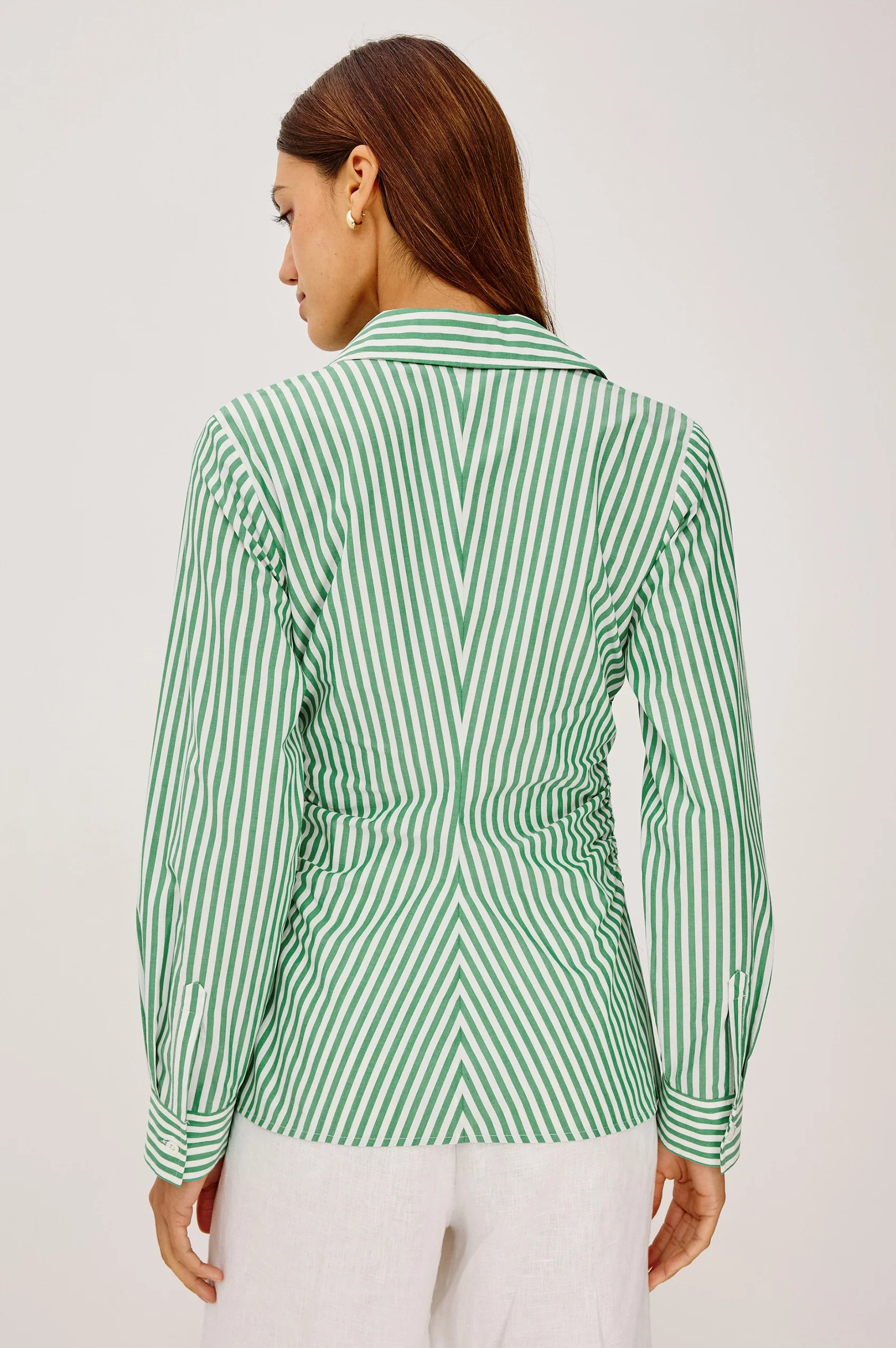 Woman wearing a green and white striped shirt on a plain background