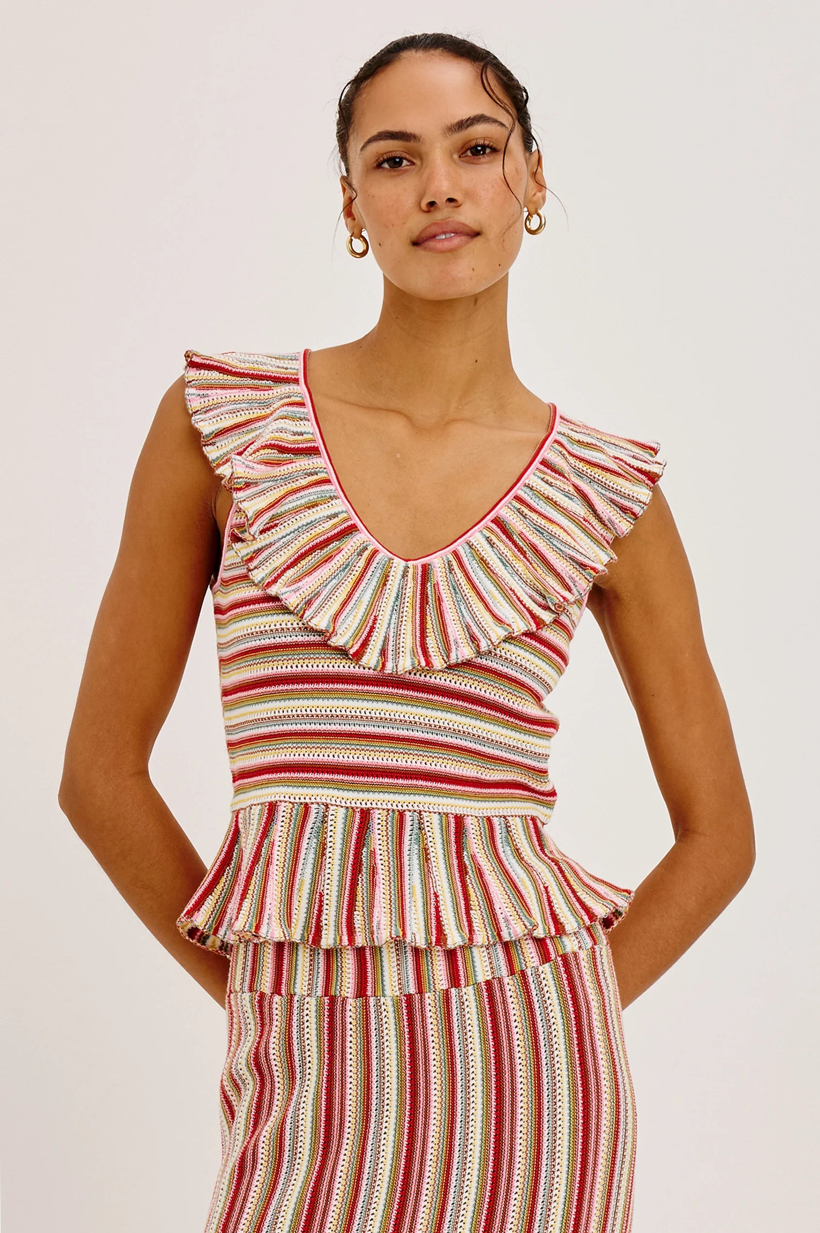 Woman wearing a colorful striped dress with ruffled details on a plain background
