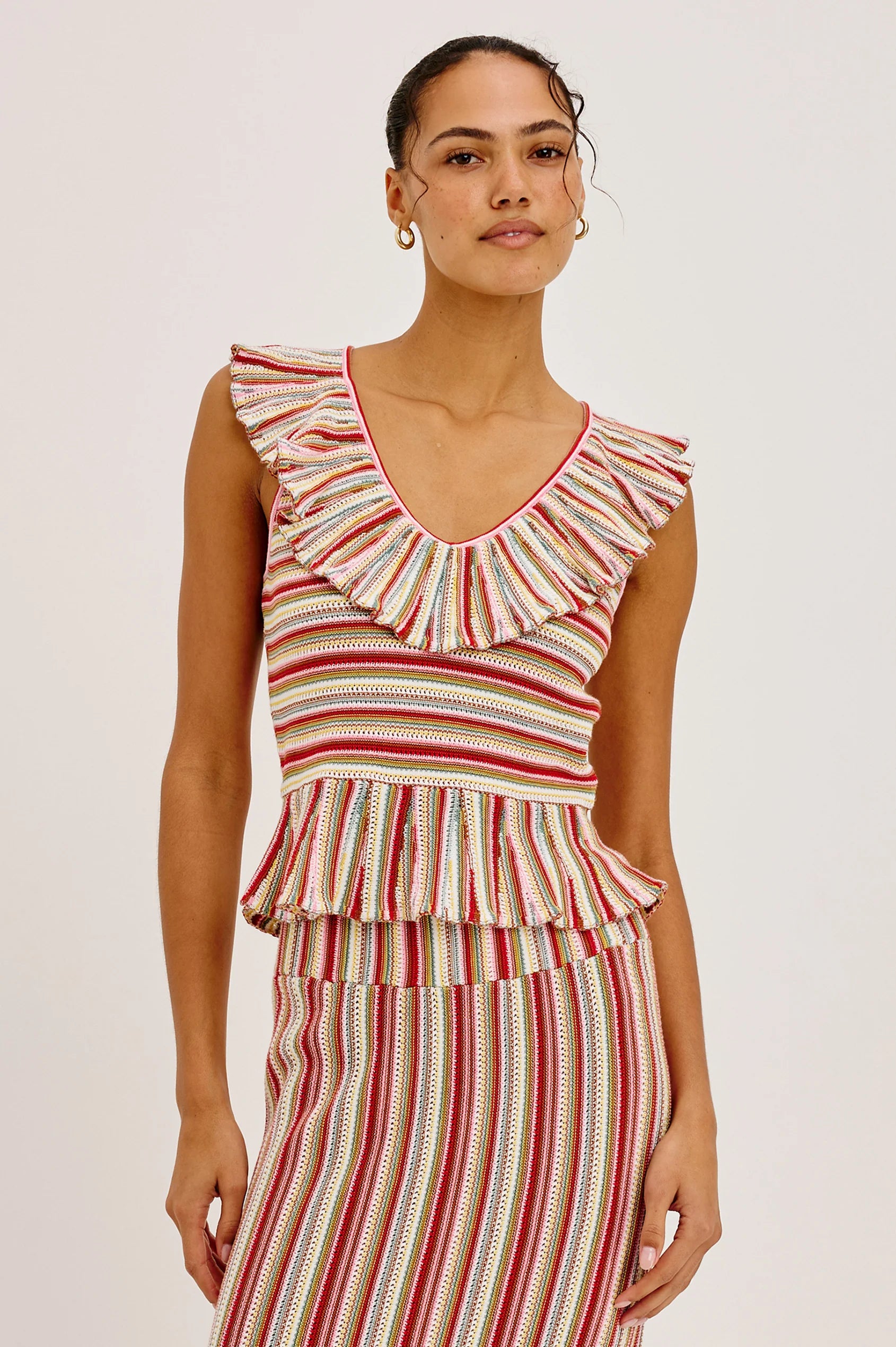 Woman wearing a red and white striped dress with ruffled top on a plain background