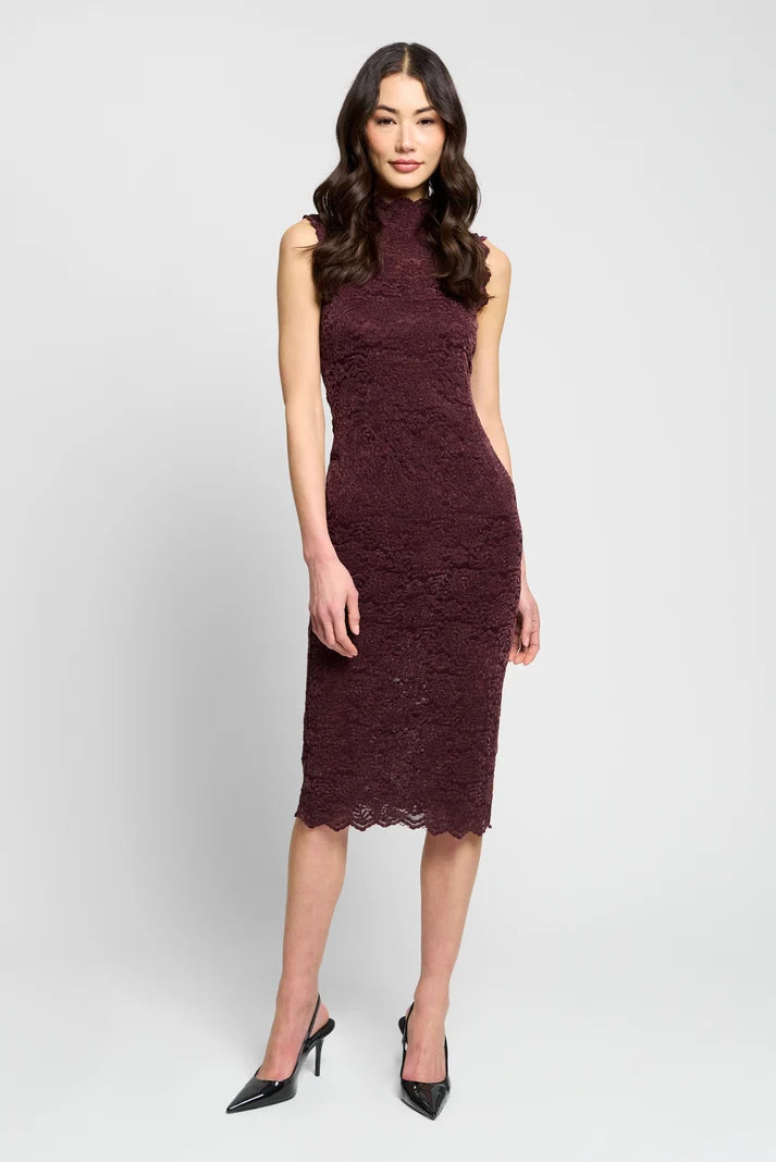 A woman modeling a sleeveless, high-neck, knee-length lace dress in a deep burgundy color, paired with black pointed-toe heels, against a light gray studio background.