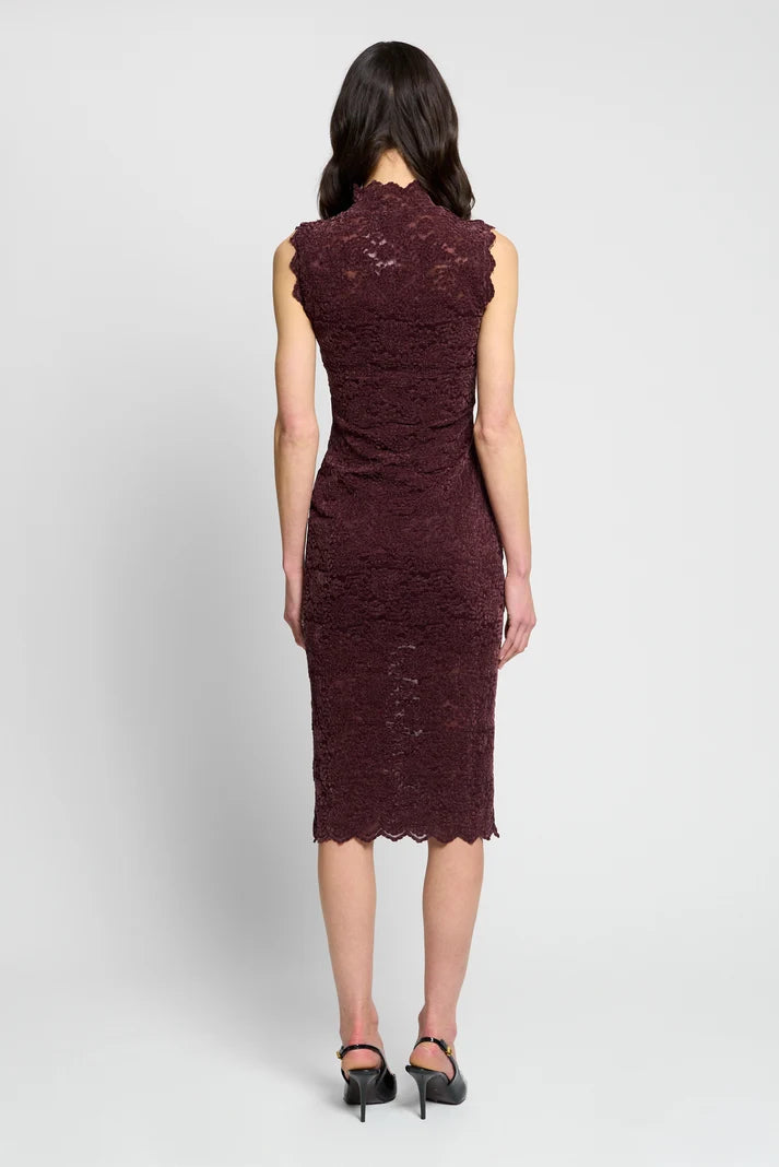 A woman viewed from the back wearing a sleeveless, knee-length lace dress in a deep burgundy or maroon shade, paired with black high heels, against a light gray studio background.