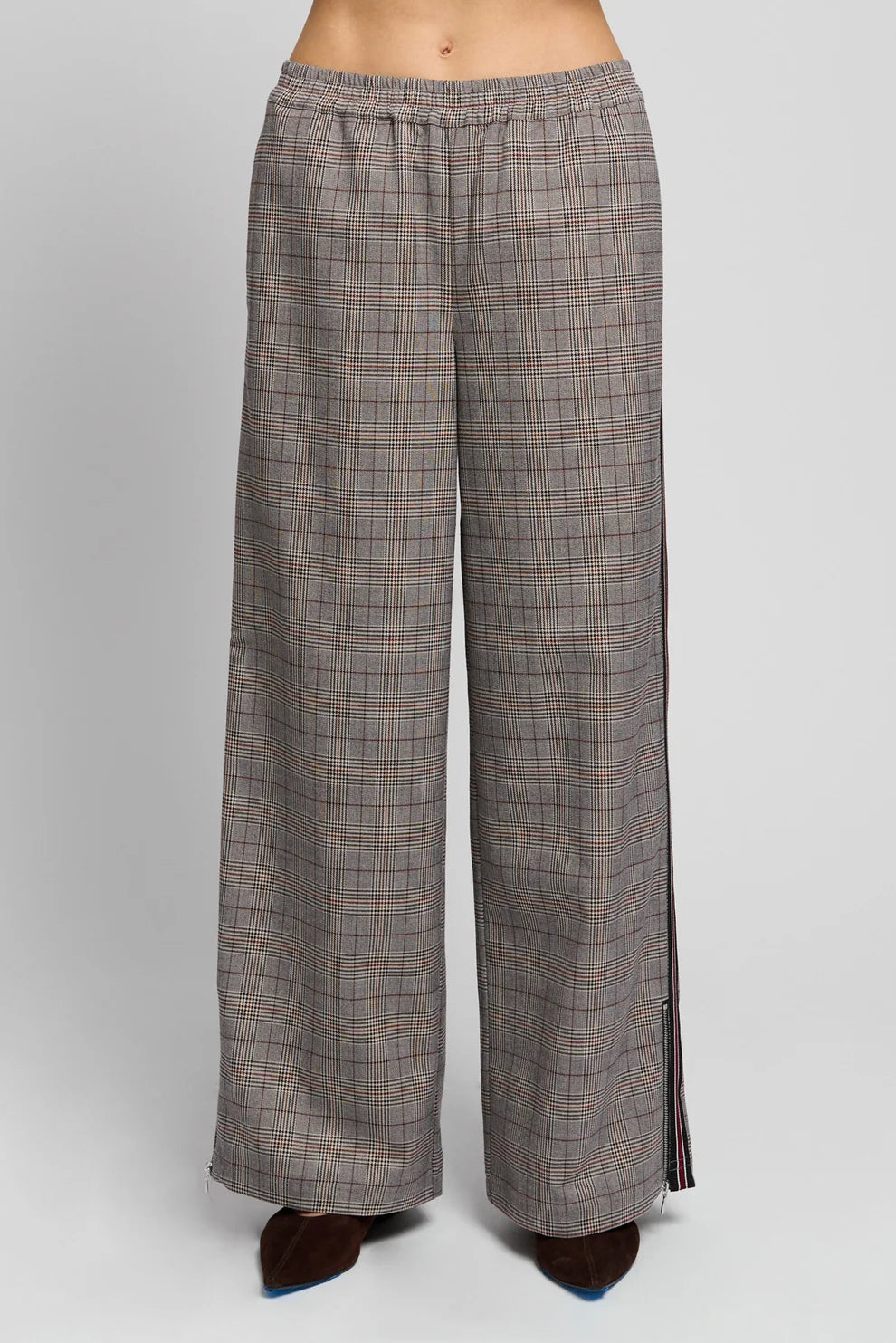 A pair of wide-leg plaid trousers in a gray and brown check pattern, shown on a model from the waist down against a light gray studio background.