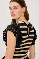Woman wearing a black and beige striped crochet top on a white background