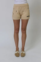 Beige knitted shorts worn by a person on a white background
