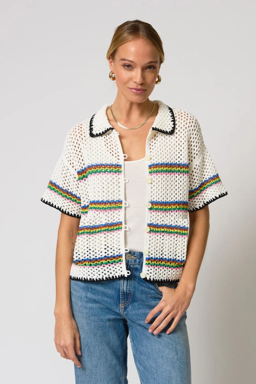 Woman wearing a colorful knit cardigan with a plain background