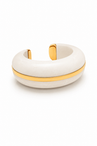 A thick, dome-shaped cuff bracelet made of textured off-white resin with a polished gold metal band running horizontally through the center and gold end caps, shown on a clean white background.