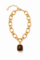 A gold-tone chain necklace with a large oval link design and a dark brown cylindrical pendant, shown on a plain white background.