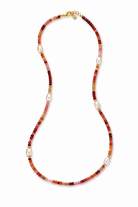 A beaded necklace featuring alternating strands of warm red-orange beads and white baroque pearls, accented with small gold spacer rings and a gold clasp, shown on a plain white background.