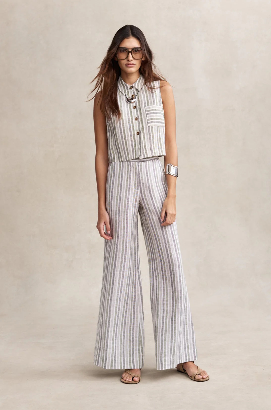 Woman wearing a striped sleeveless top and wide-leg pants on a beige background