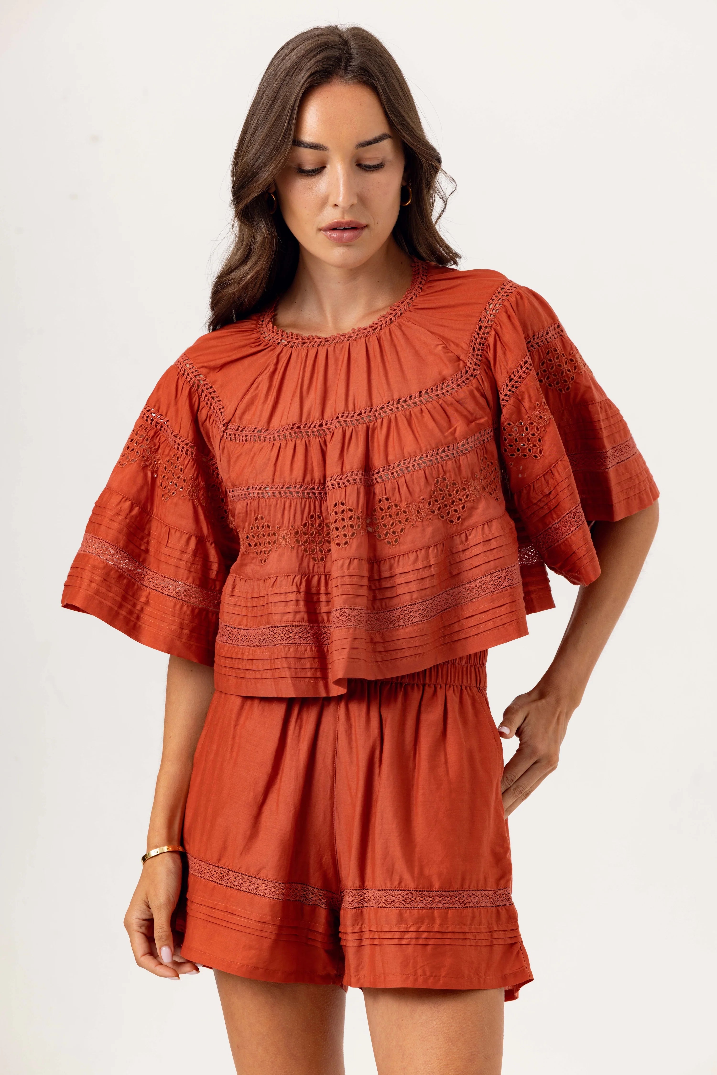 Woman wearing a rust-colored dress with embroidery on a white background