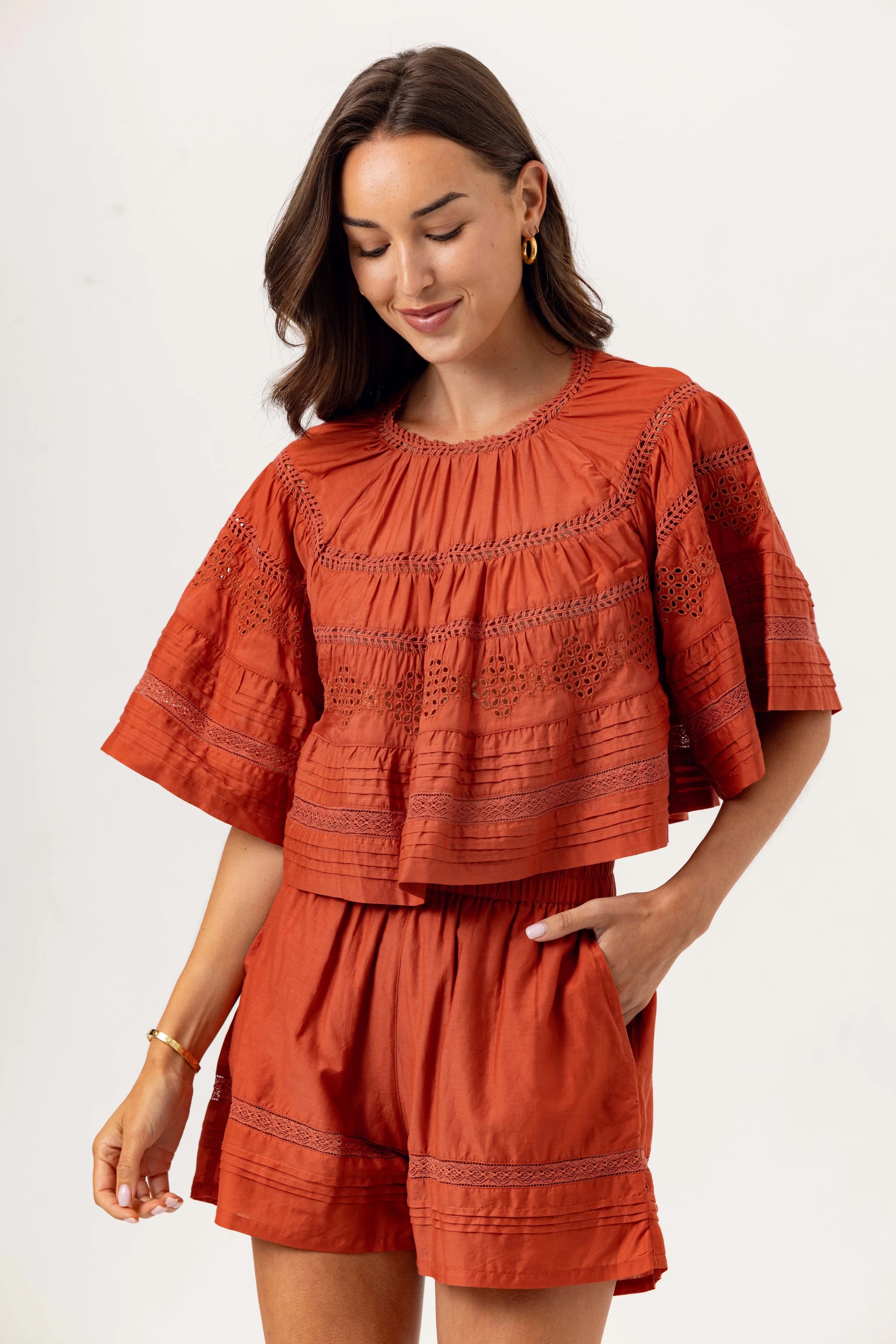 Woman wearing a rust-colored outfit with embroidered details on a white background