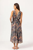 Woman wearing a patterned dress with an open back on a white background