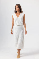Woman wearing a white sleeveless dress on a plain background