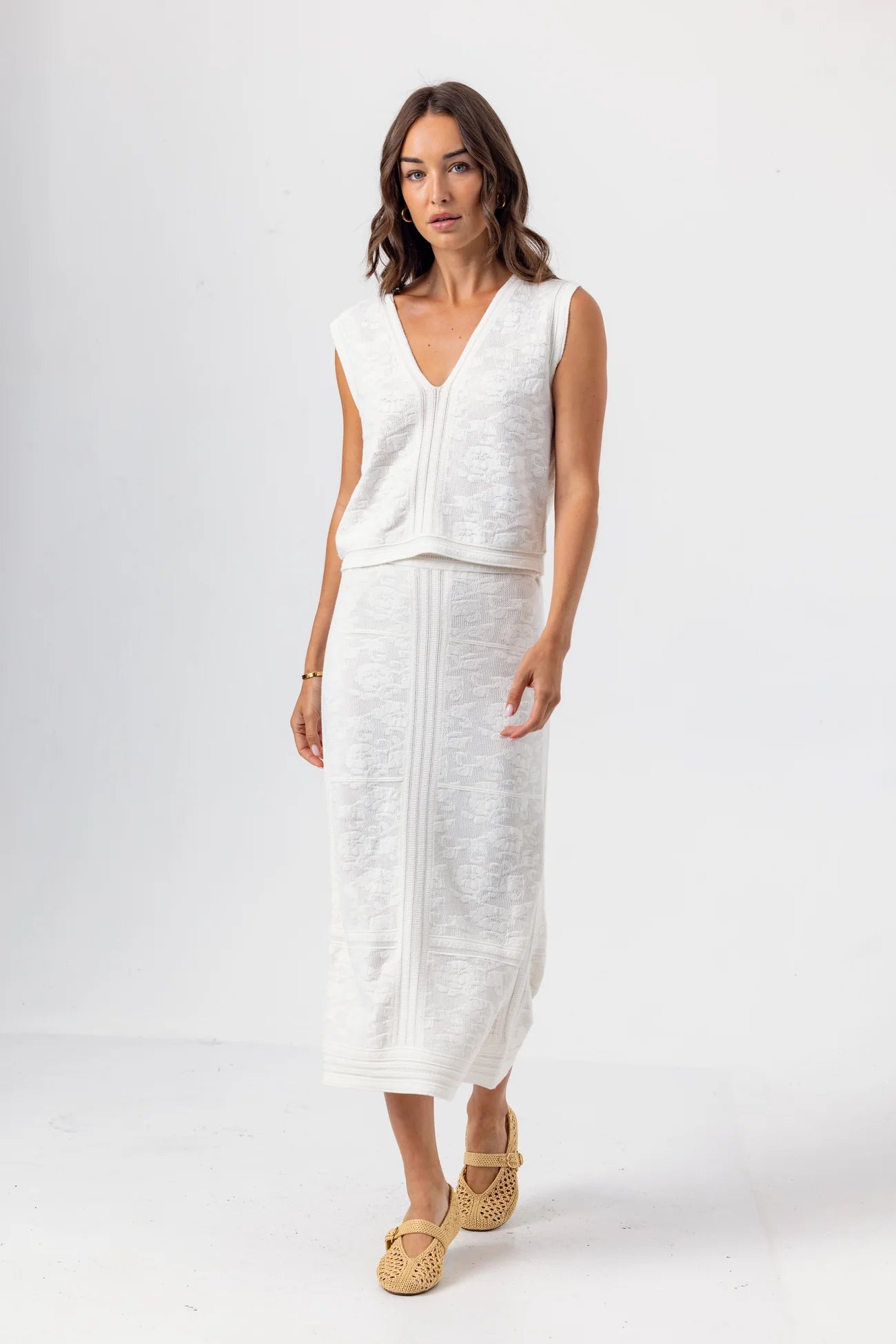 Woman wearing a white sleeveless top and skirt set on a white background