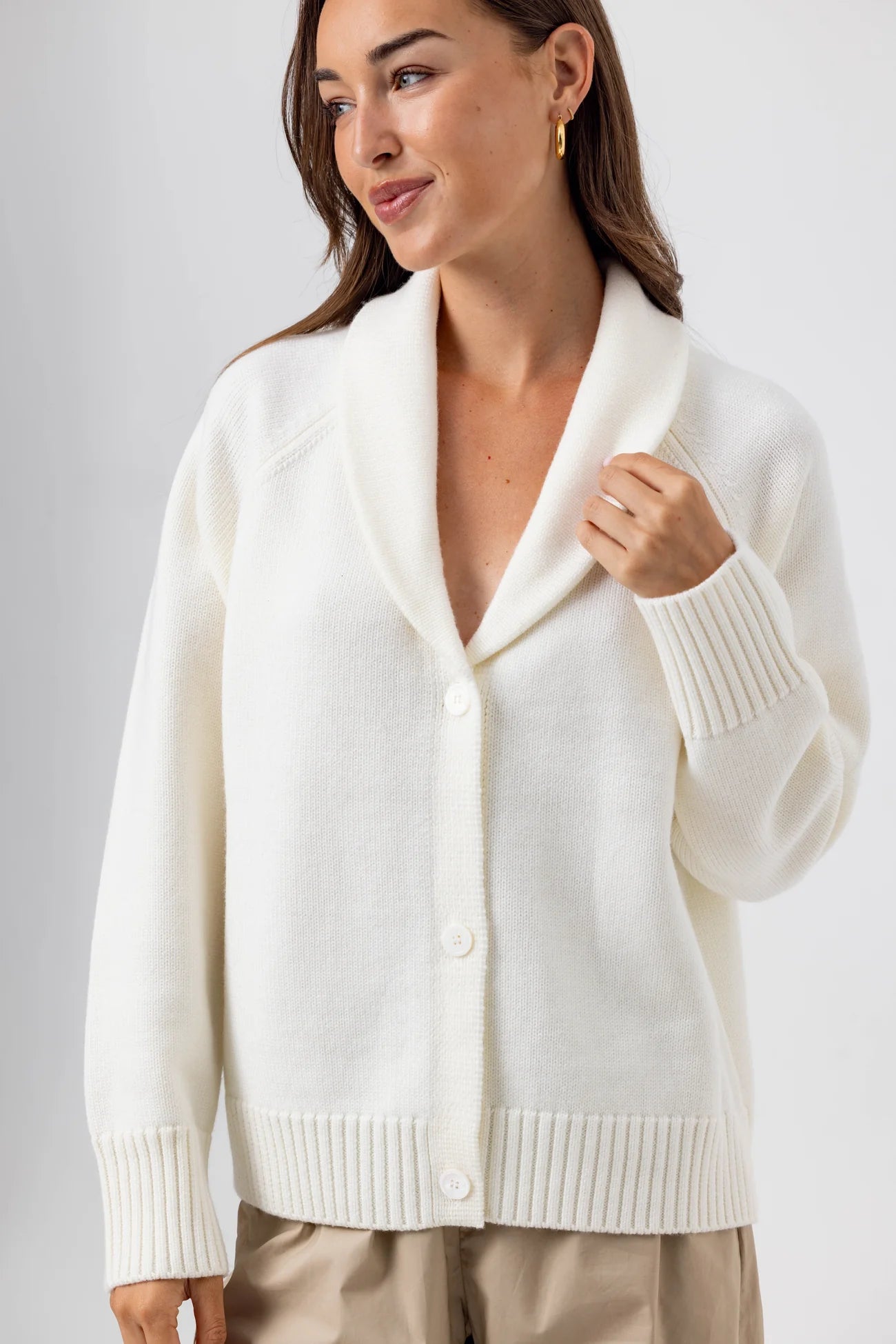 Woman wearing a white cardigan against a plain background