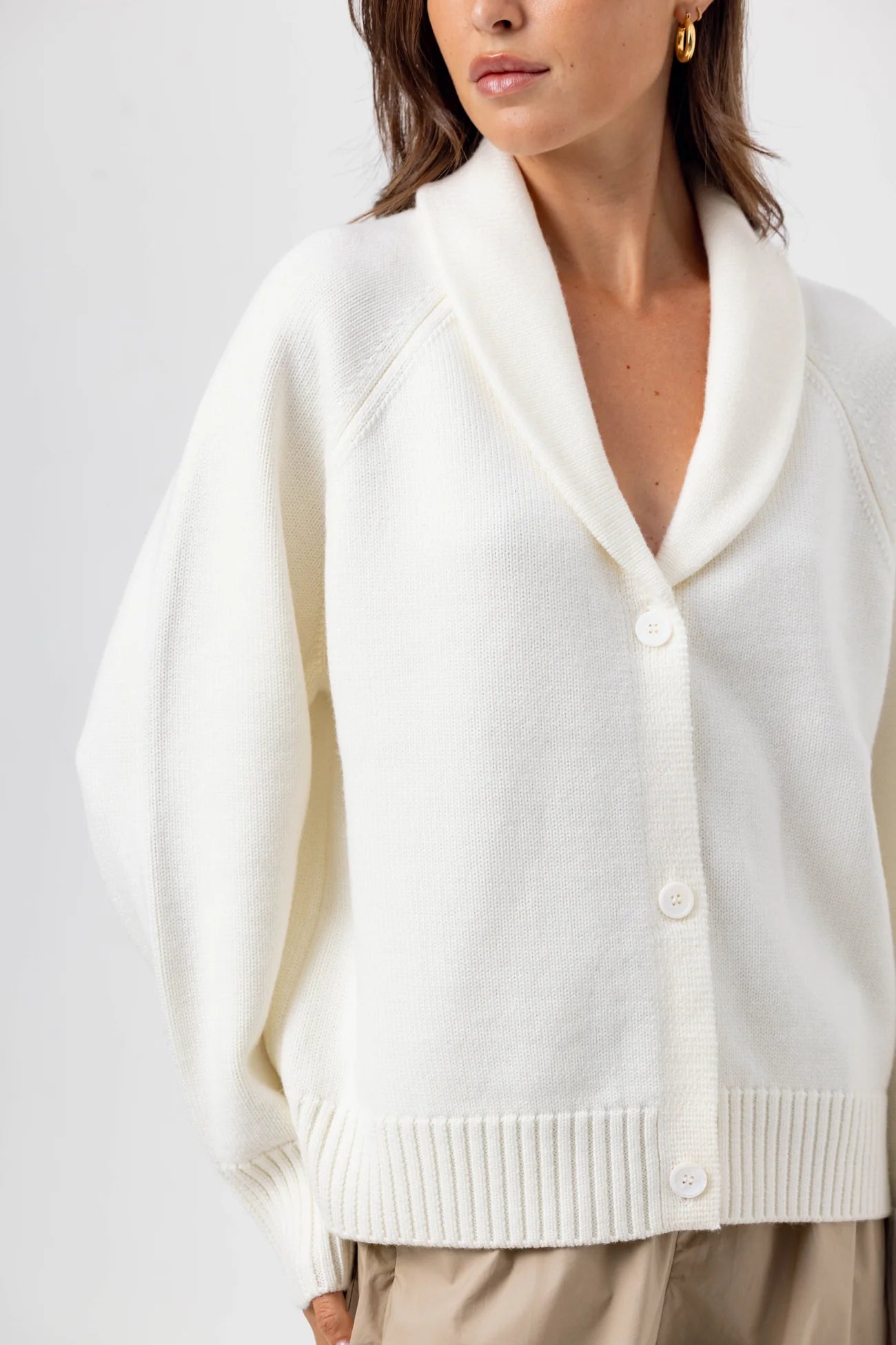 White cardigan worn by a person on a white background