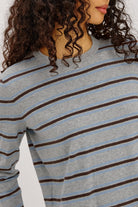 Close-up of a person wearing a gray and blue striped long-sleeve shirt.
