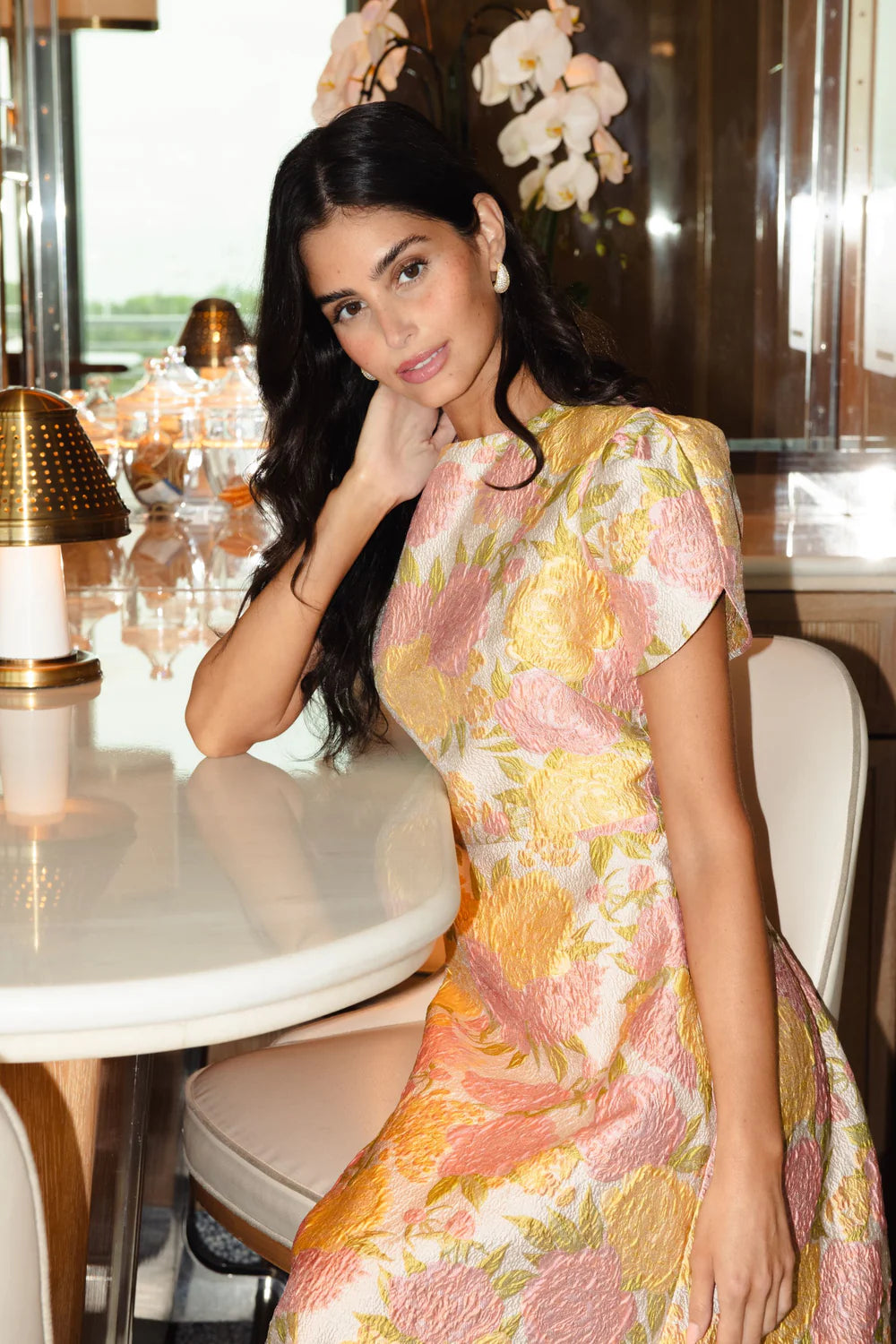 Woman in a floral dress sitting at a table in a restaurant.