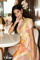 Woman in a floral dress sitting at a table in a restaurant.
