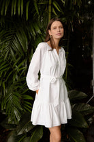 Woman wearing a white dress standing among green foliage