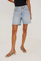 Person wearing light blue denim shorts on a plain background
