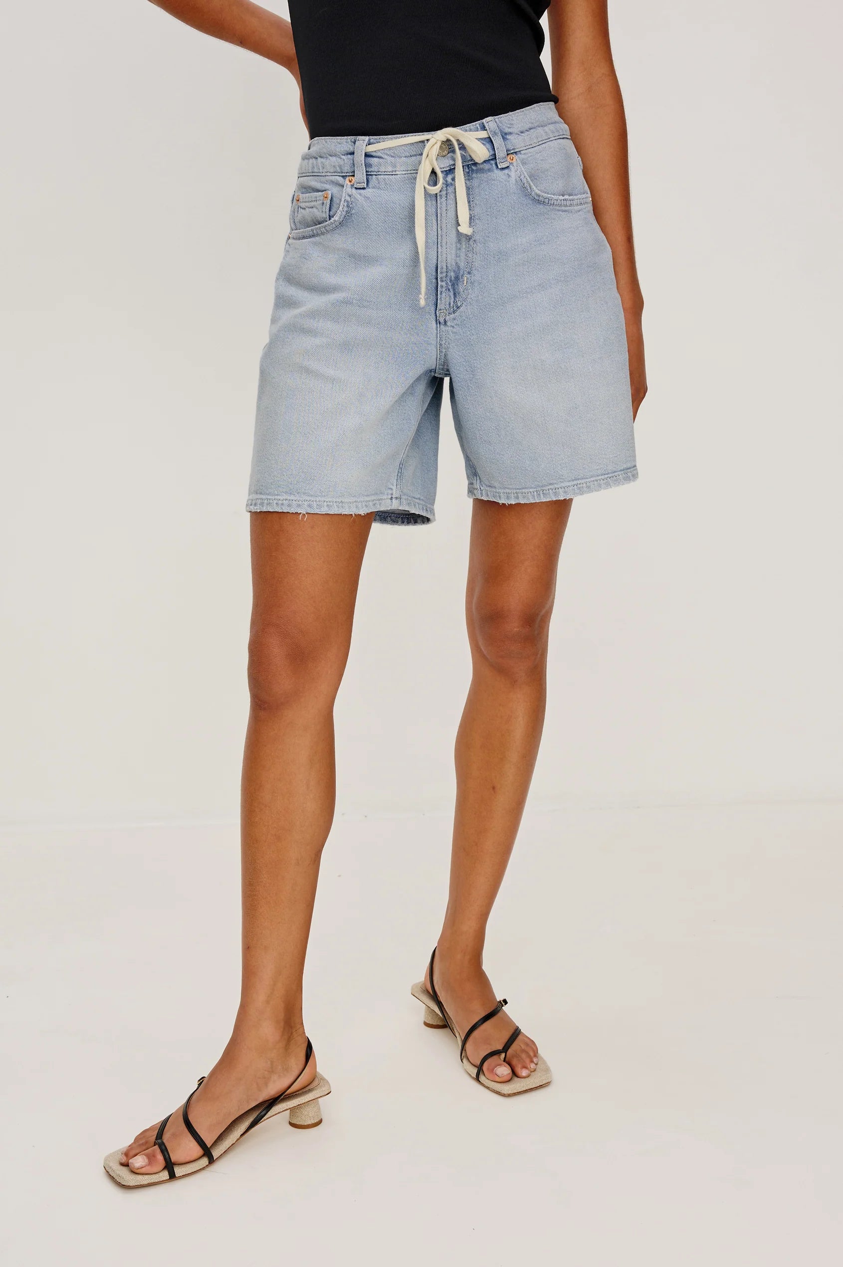 Person wearing light blue denim shorts on a plain background